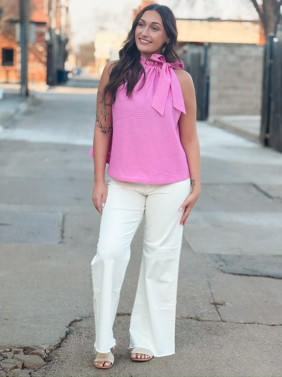 Textured pink top featuring a feminine bow tie neckline and relaxed fit