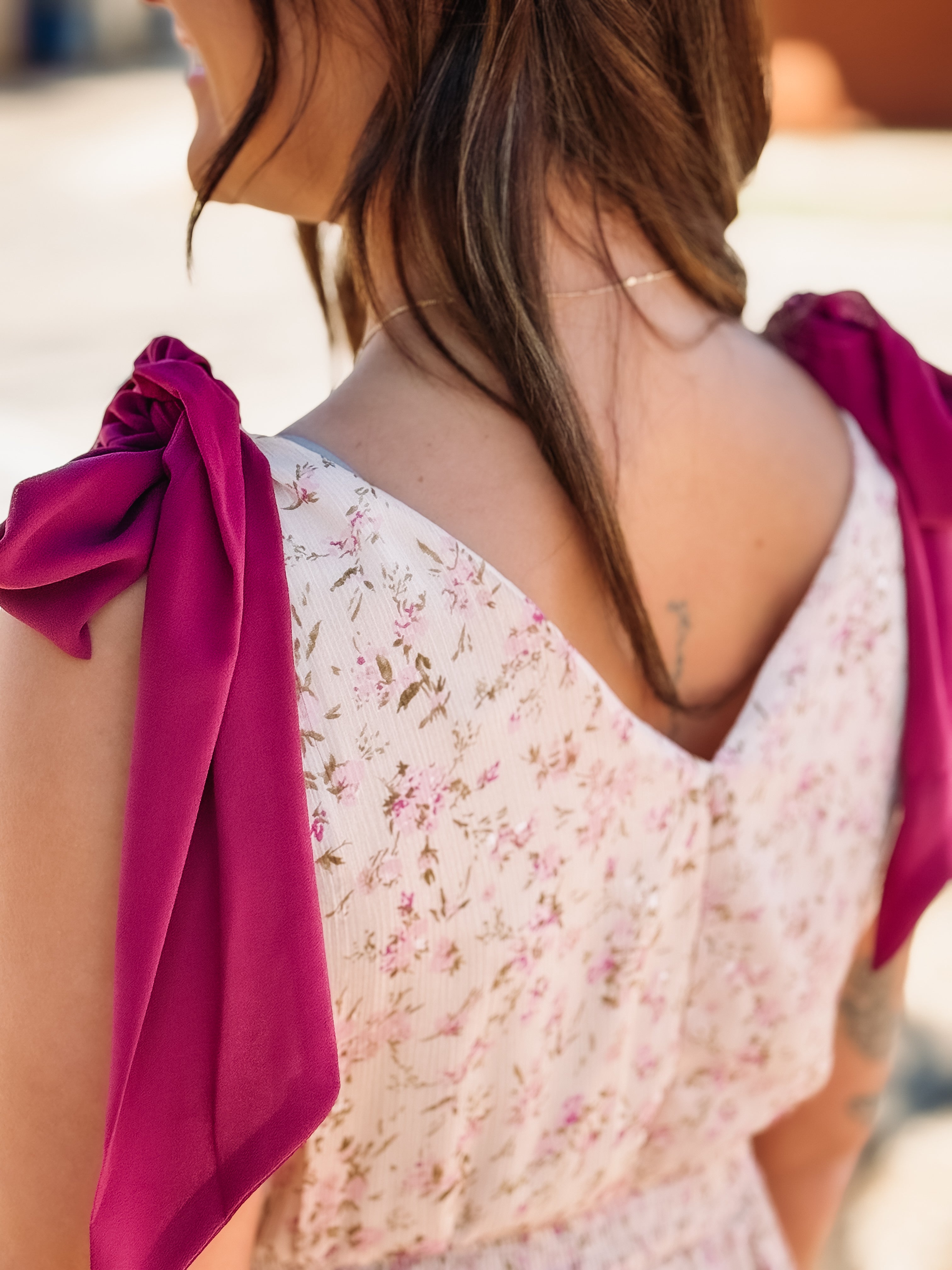 Woman wearing a floral dress with pink sleeves, blurred background