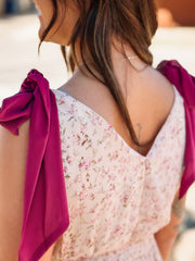 Woman wearing a floral dress with pink sleeves, blurred background