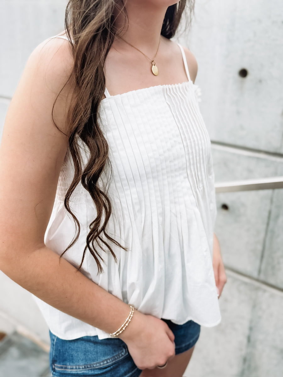 White pintuck spaghetti strap top with adjustable straps and a fit and flare look.