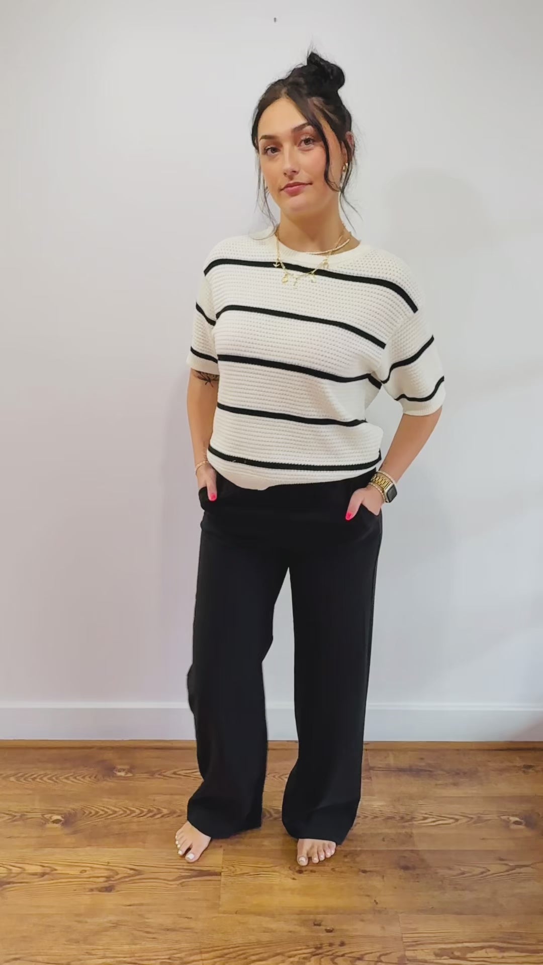 black dress pants paired with a white and black striped knit top.