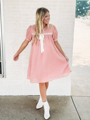 Dusty pink short sleeve baby dol dress with white bow detailing.