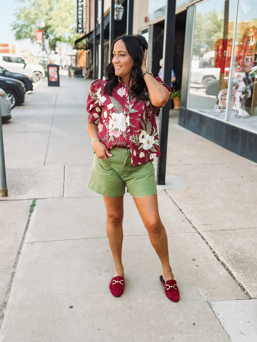 Wine-colored floral blouse with a ruffle neckline and button-up front
