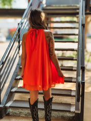 Bright orange mini dress with a mock neck, self-tie neckline, flowy silhouette, and tiered skirt.