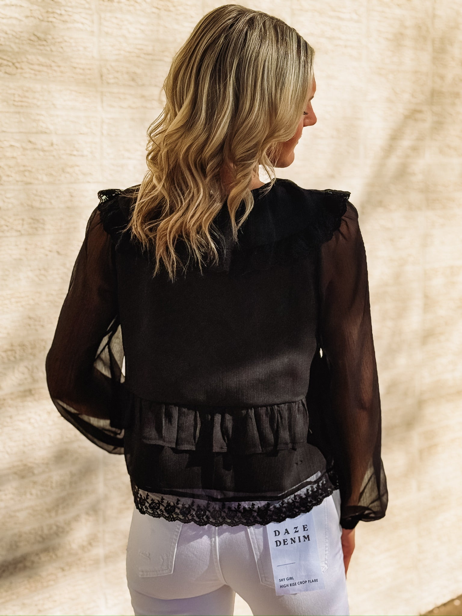 Black long-sleeve blouse featuring a wide ruffled collar with lace trim, sheer balloon sleeves, a ruffled bodice detail, and an intricate lace hemline