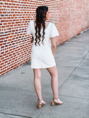 White mini dress featuring short puff sleeves, a flattering body-con silhouette, and a square neckline. Designed in a textured waffle knit for added detail and dimension.
