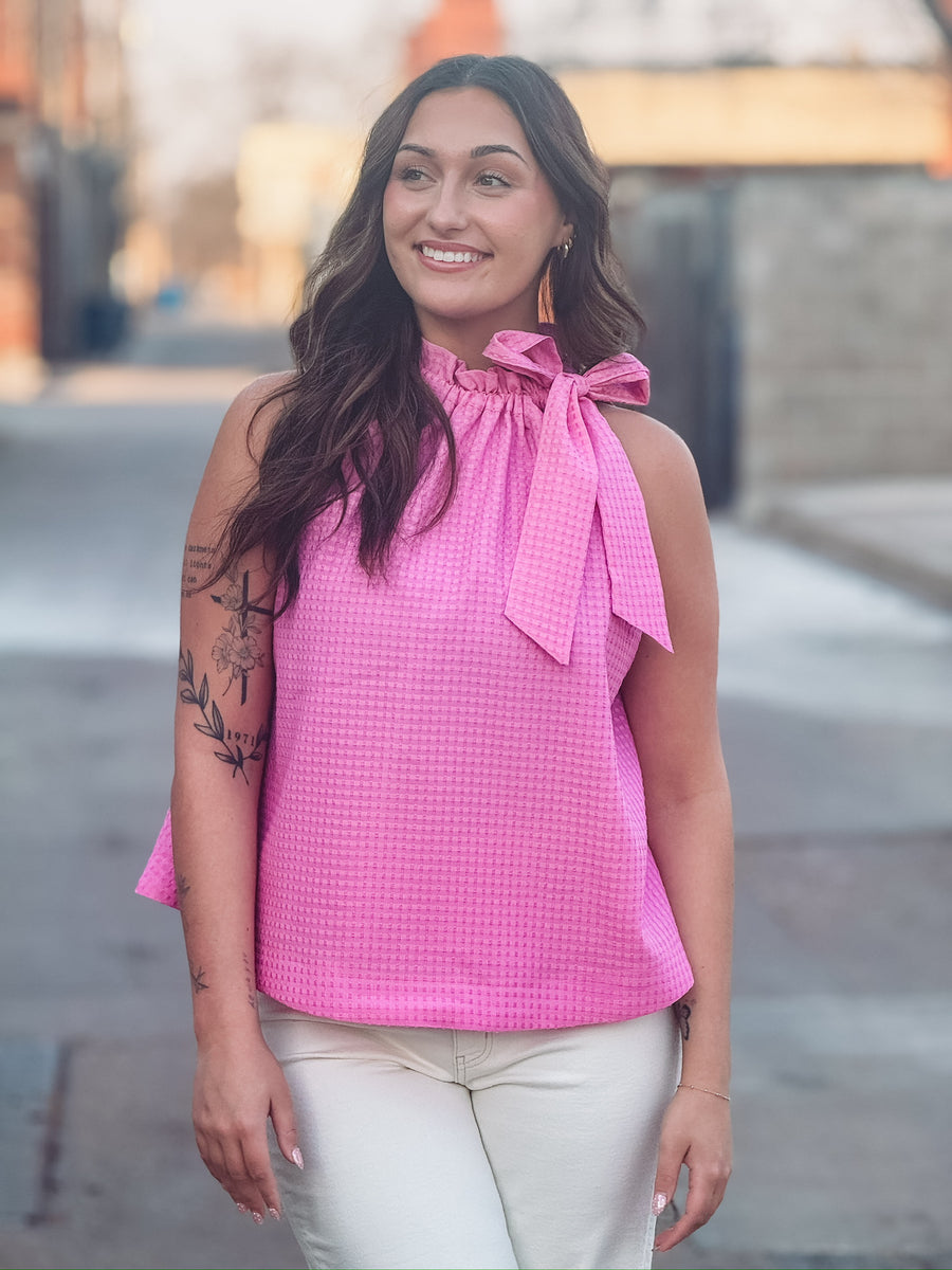 Textured pink top featuring a feminine bow tie neckline and relaxed fit