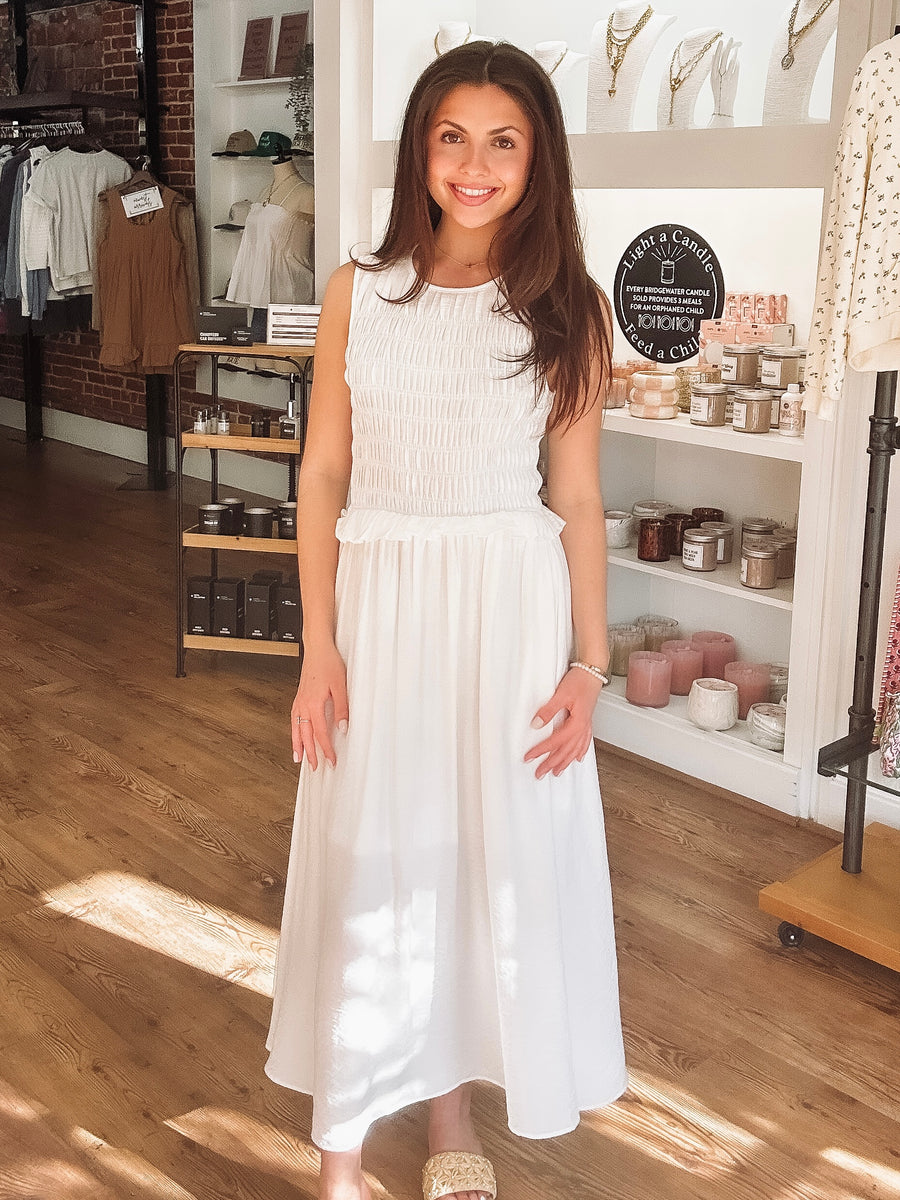 Woman in a white dress standing in a store with shelves in the background