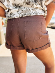 Light wash denim shorts with front pleats and a soft rolled hem, featuring a relaxed, casual fit