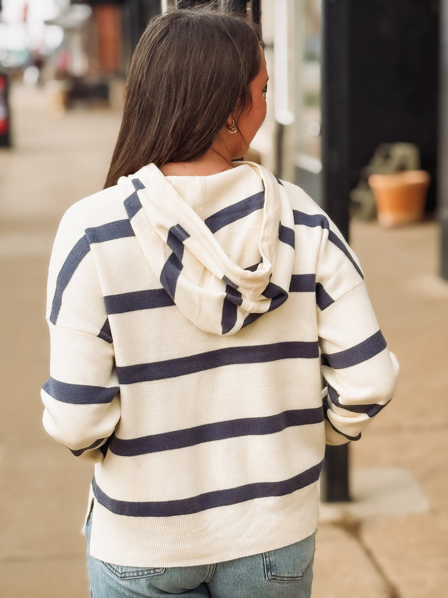 Person wearing a striped hoodie walking on a sidewalk