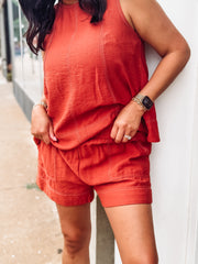 Person wearing a rust outfit standing against a white wall.