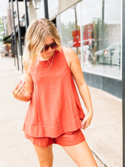 Woman wearing a coral sleeveless top and shorts on a city street.
