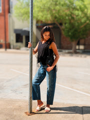 Black textured knit sweater vest with a v-neckline, ribbed trim, and open sides finished with adjustable sheer tulle tie details. Lightweight knit that can be worn alone or layered.