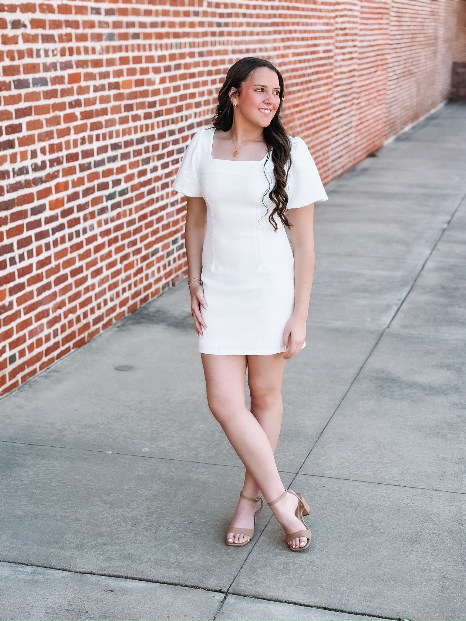 White mini dress featuring short puff sleeves, a flattering body-con silhouette, and a square neckline. Designed in a textured waffle knit for added detail and dimension.