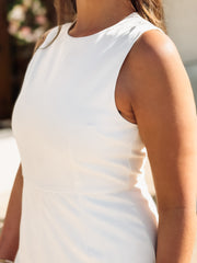 Person wearing a white sleeveless top with blurred background
