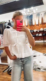 white peplum top with cut out eyelet details and bow tie front