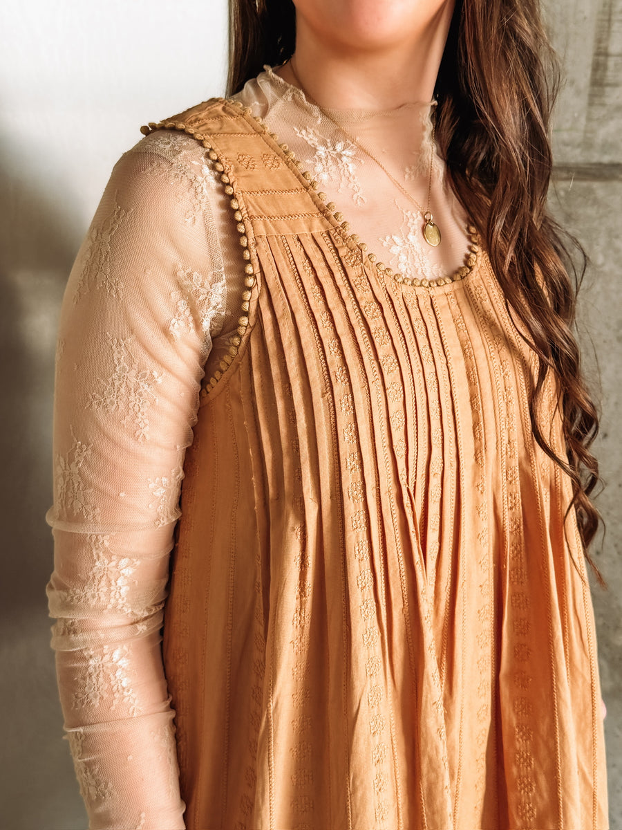 Camel colored embroidered sleeveless mini dress with ruffle hem and pleated detailing.