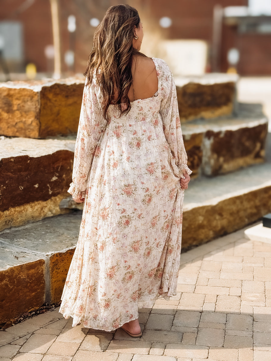 Woman in a floral dress standing on stone steps with a blurred background