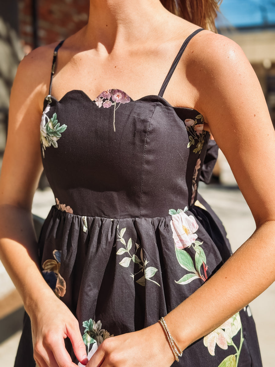 Black dress with floral patterns worn by a person, blurred background