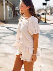 Woman wearing a light-colored checkered outfit on a city street.