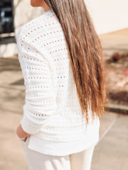 White crochet top worn by a person with blurred background