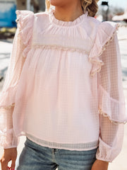 Light pink blouse with ruffled sleeves and neckline worn by a person.