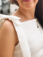 Close-up of a person wearing a white sleeveless top with a blurred background
