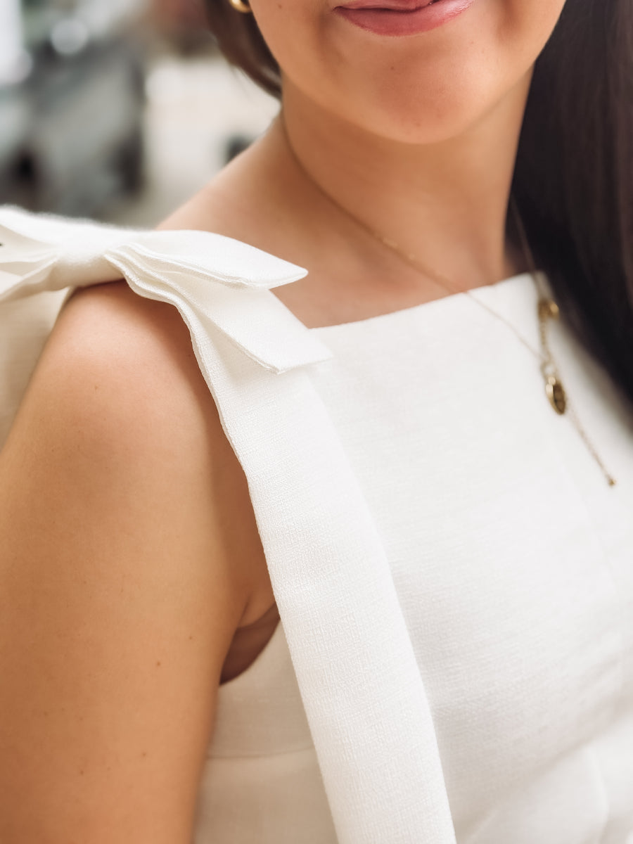 Close-up of a person wearing a white sleeveless top with a blurred background