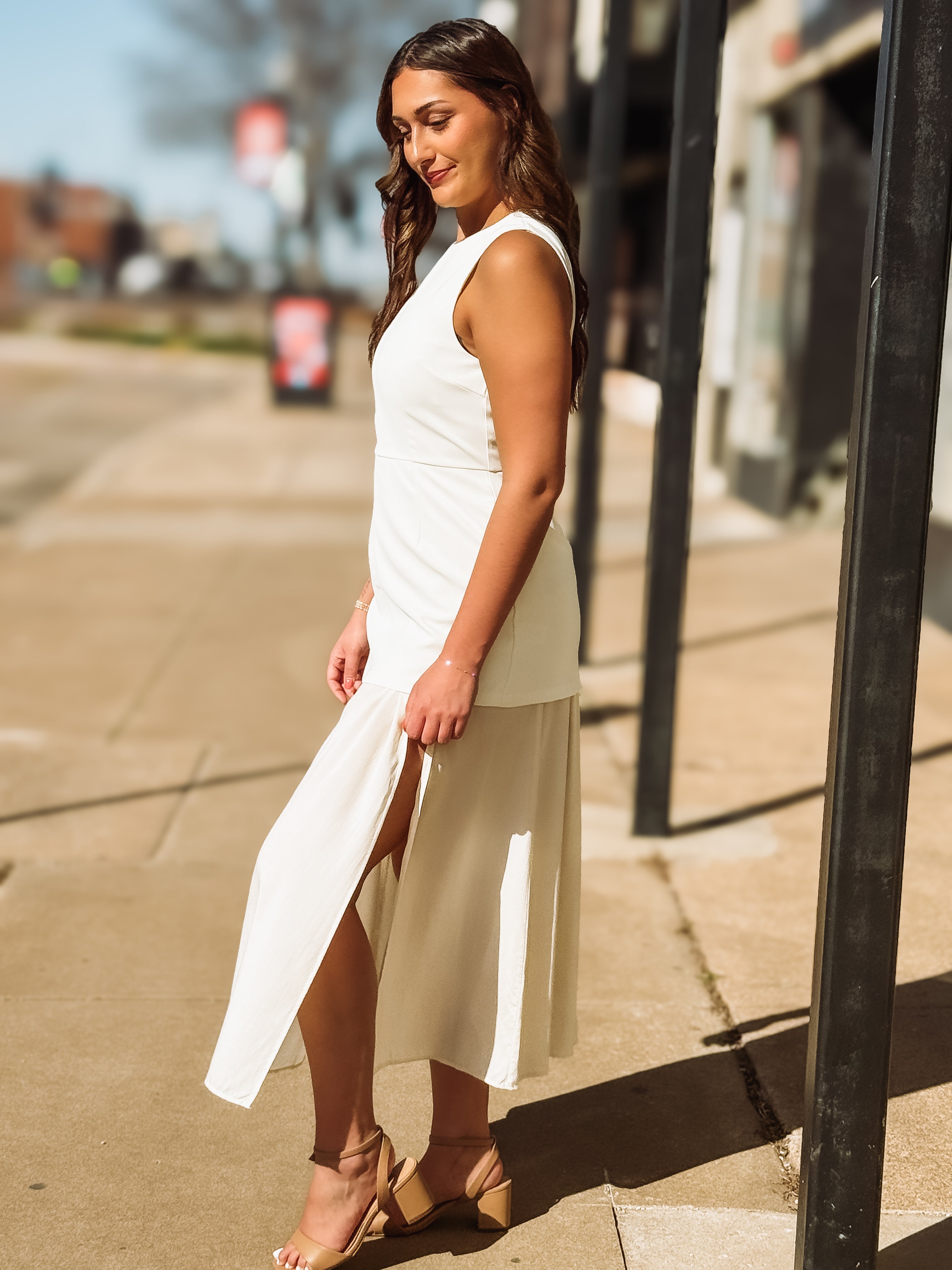 Woman in a white dress standing on a sidewalk