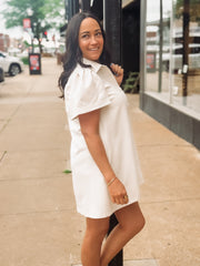 Woman in a white dress standing on a sidewalk