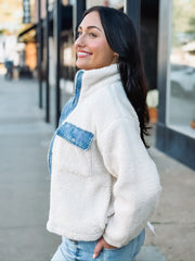 Cropped cream sherpa jacket with denim detailing on zipper and front pockets.